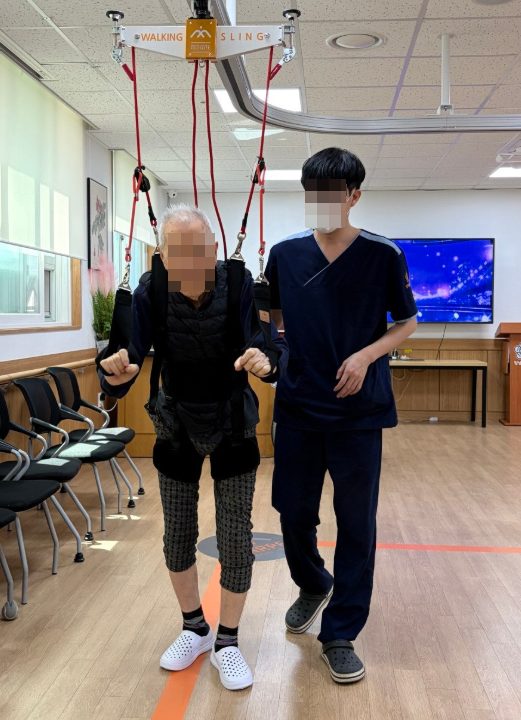 워킹레일에서 보행 훈련을 하시는 어르신과 직원